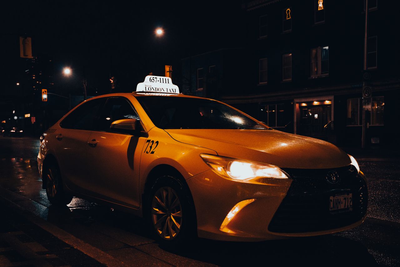 A yellow taxi waiting at night in London, Ontario, Canada. Urban transportation captured with street lights.