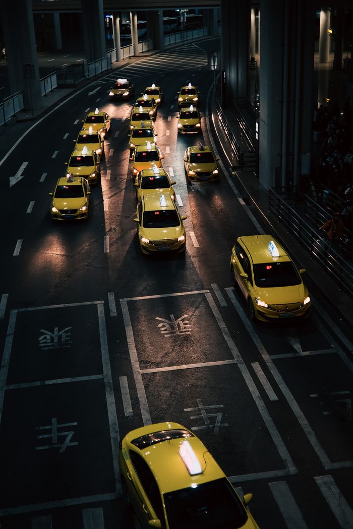 Mastering the First Impression: Your intriguing post title goes here High angle view of lined yellow taxis on urban street during nighttime.